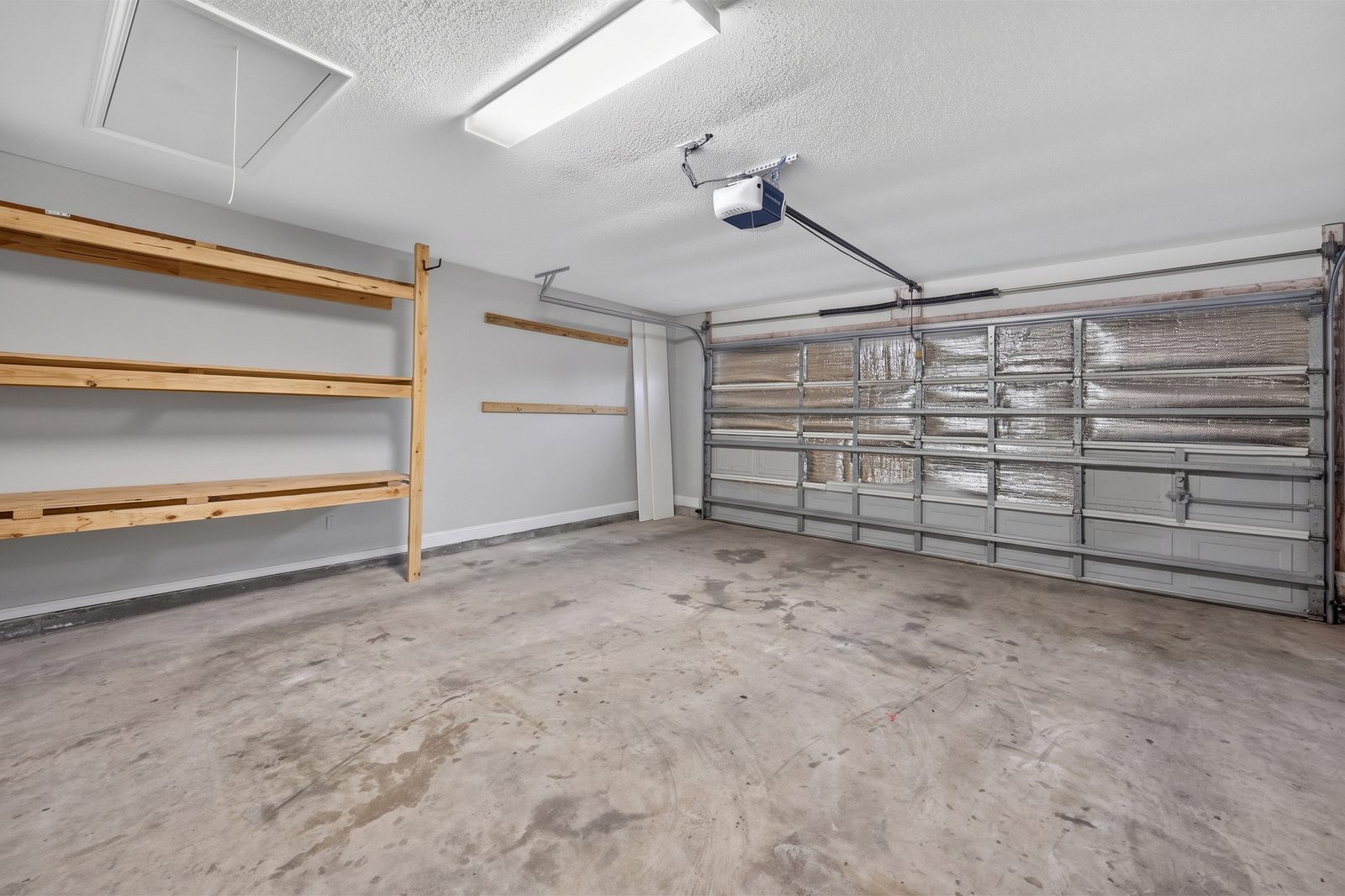 Two-car garage with built-in wood shelving and an automatic door opener